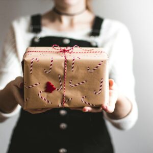 tilt-shift lens photography of woman holding candy cane-print gift box in a well-lit room